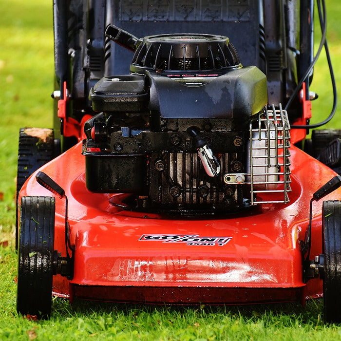 Front-view of a red push lawn mower on a green lawn