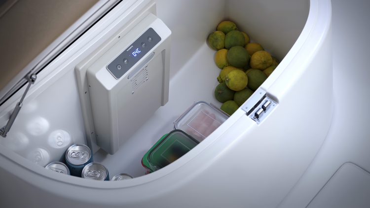 A compartment with limes and canned drinks with a Dometic cold machine mounted to a wall on a white background