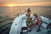 Two people on a boat at sunset with an open Dometic cooler.