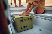 Person sitting on a boat with a green Dometic cooler box in the foreground