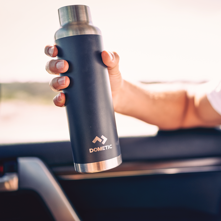 Person holding a Dometic water bottle inside a vehicle