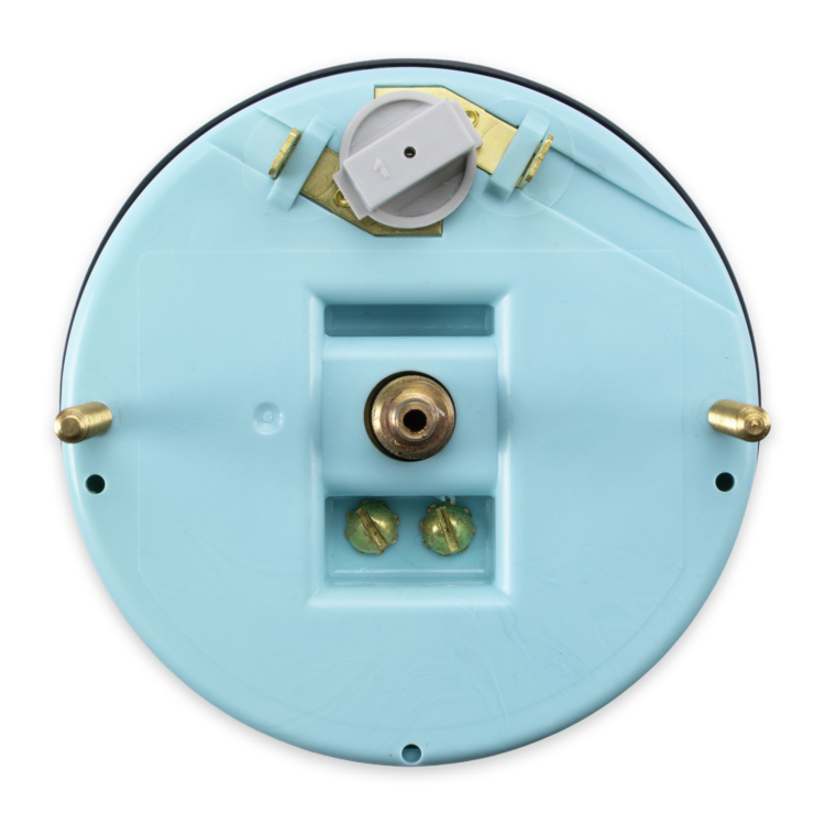 The underside of a circular speedometer, showing brass-colored metal terminals, a central post, and a white plastic component near the top, isolated on a white background.