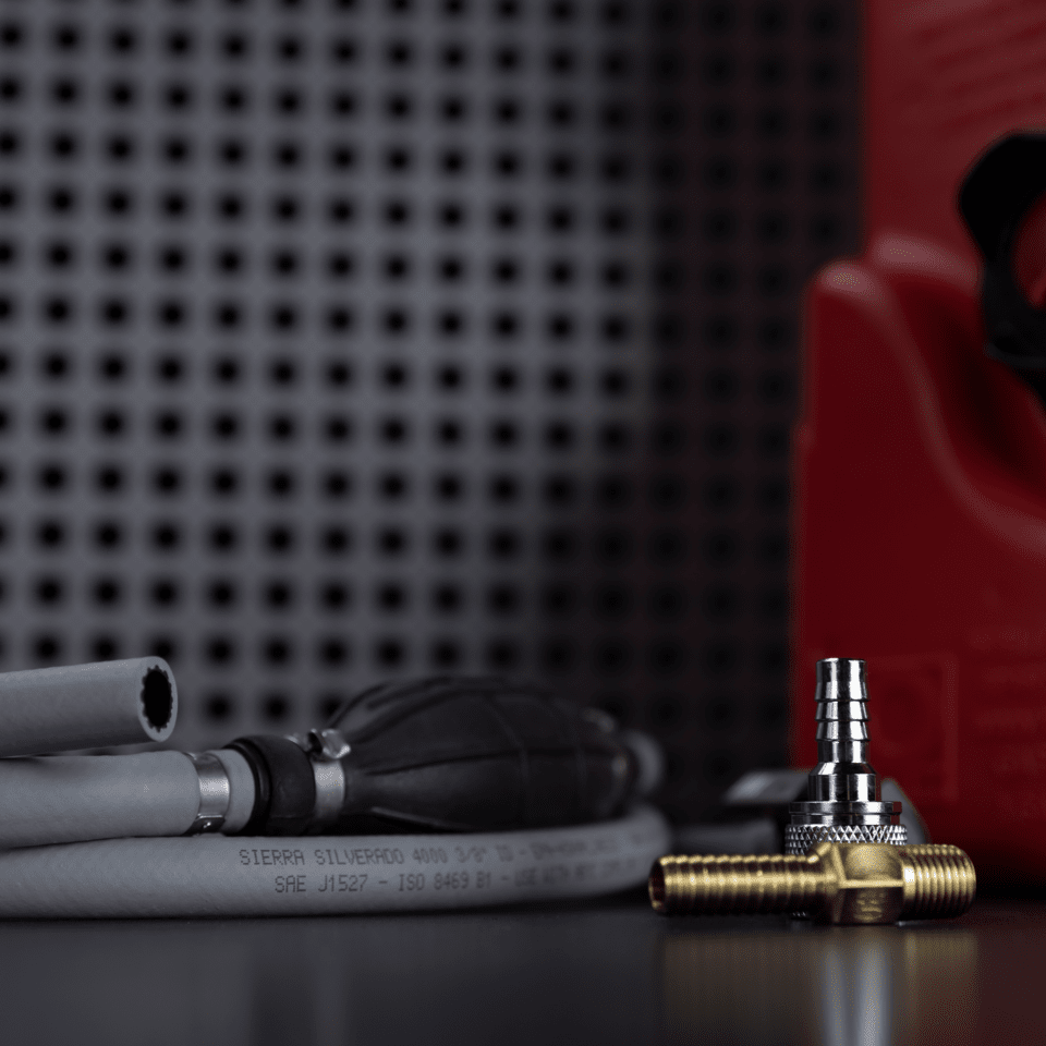 A Sierra / Moeller fuel line assembly, fuel connectors, and a red portable fuel tank on a black table.