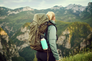 Person with a large backpack and water bottle standing on a mountain top