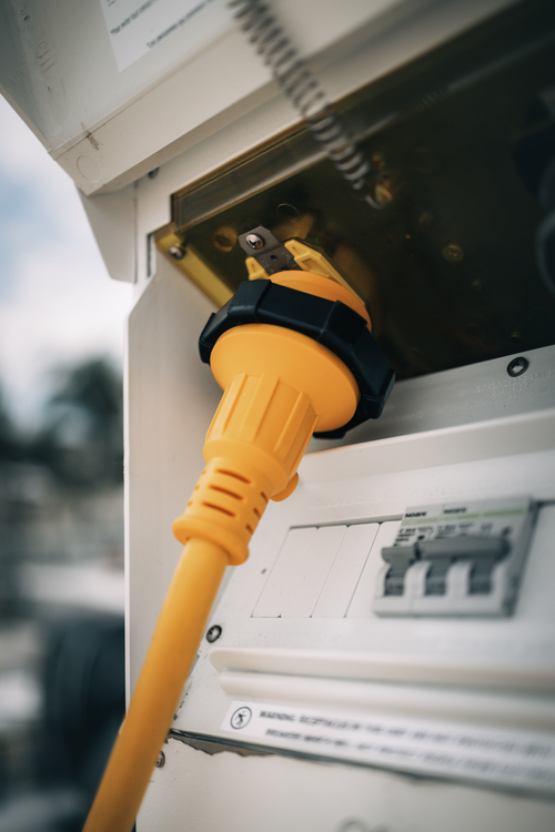 Yellow shore power cord plugged into a dockside power outlet.