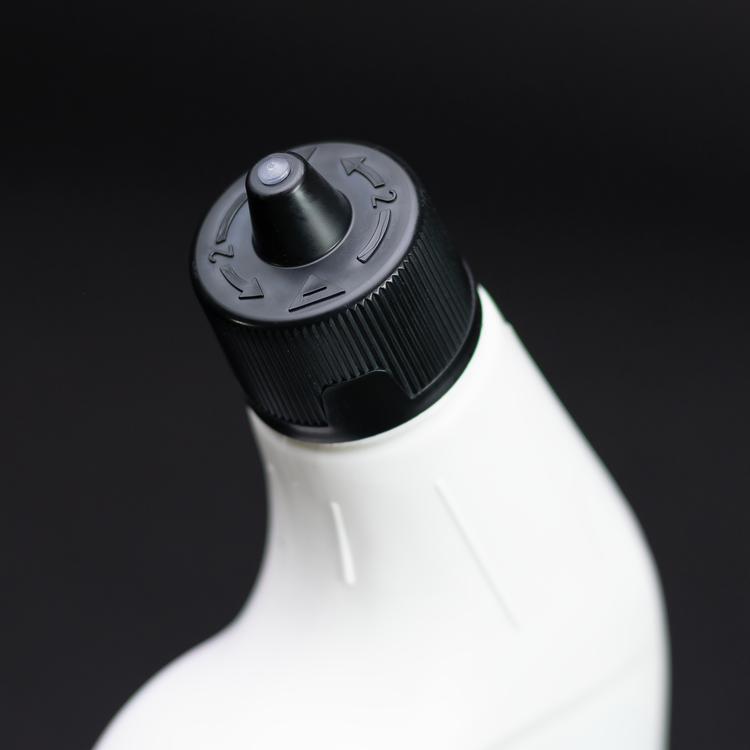 Close-up of a white bottle with a black cap on a dark background