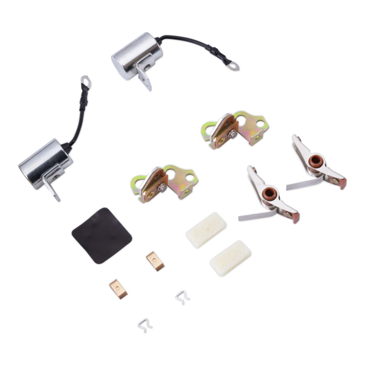 A tune up kit with hardware laid out on a white background, including two silver cylindrical units with black wires, two gold-toned metal clips, two silver-and-copper contact points, two small copper terminal pieces, two white rectangular pads, and a small black rubber pad.