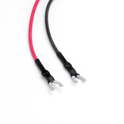 A pair of bare cable leads with red and black insulation, black heat-shrink tubing, and silver metal spade terminals on a white background.