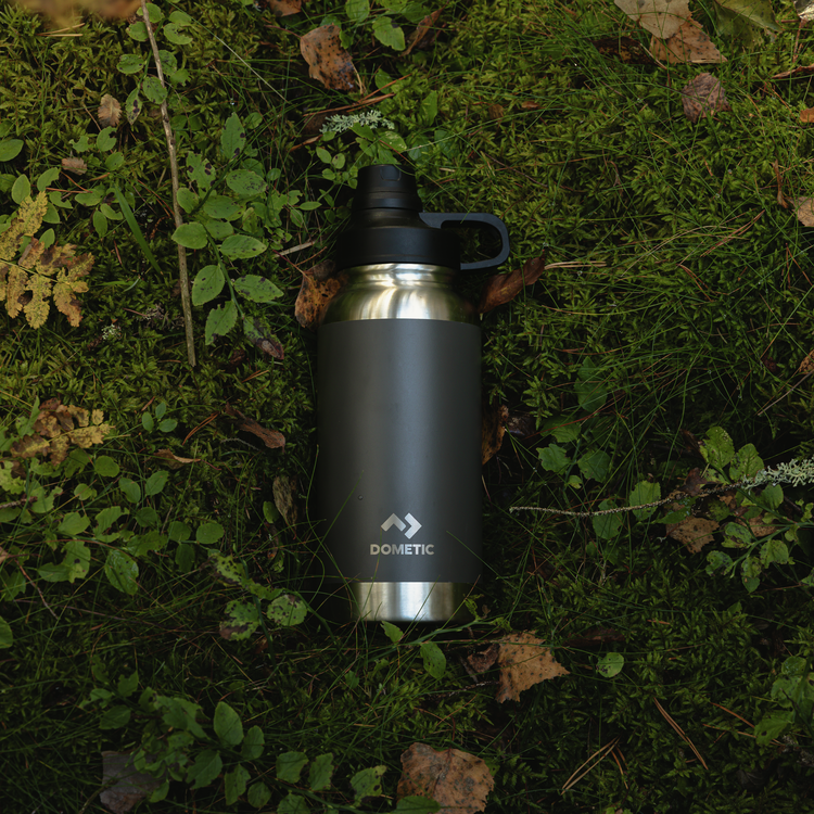 Black and silver insulated bottle on a mossy ground