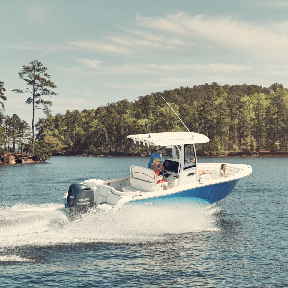 A blue and white center console boat moving through water close to shore