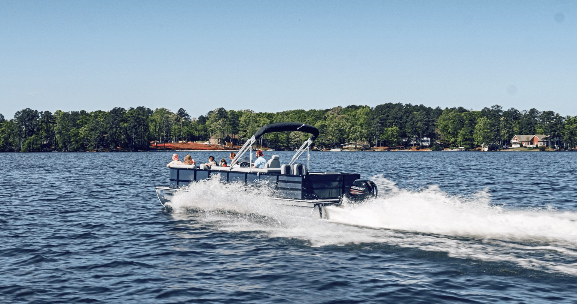 A pontoon boat full of customers moving across a lake