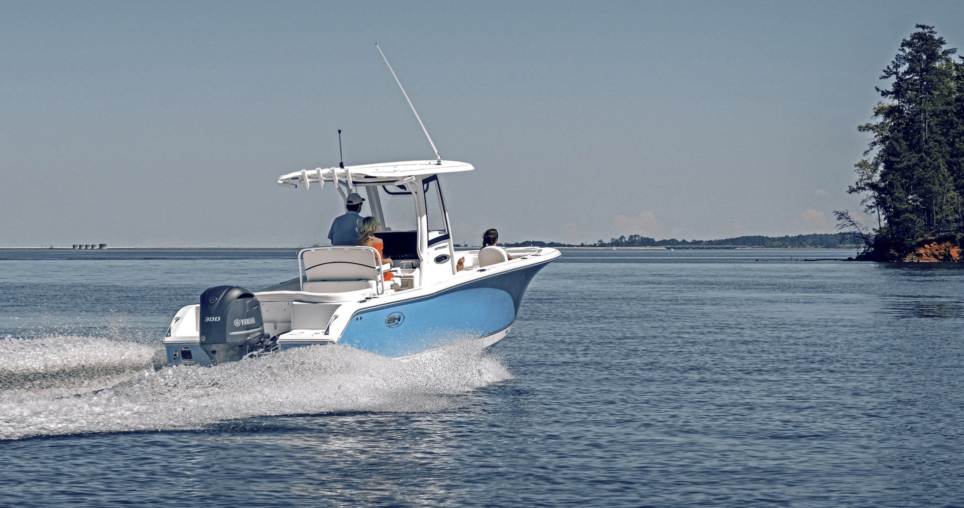 A blue and white center console boat moving close to shore